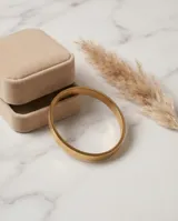 Pulsera tipo esclava rígida de acero con baño de oro, con diseño geométrico grabado en toda su superficie.