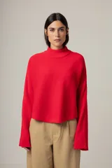 Sweater de tejido de punto en color rojo, con cuello alto y mangas largas acampanadas. Presenta un diseño de corte recto y holgado.