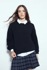 Sweater negro de tejido texturizado con líneas horizontales en relieve, de silueta levemente holgada y hombros caídos.