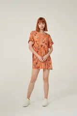 Vestido corto de viscosa con estampado floral en tonos verdes, rojos y blancos. Presenta un diseño holgado con cuello a la base y mangas cortas con volados en los extremos.