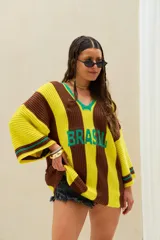 Remerón tejido de punto oversize, con diseño a rayas verticales marrones y amarillas, escote en V con ribete verde y la palabra "BRASIL" estampada en el frente.