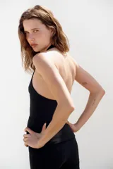 Top entallado color negro de cuello halter, con escote en V pronunciado, espalda descubierta y cierre frontal con ganchos metálicos.