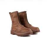 Bota de caña media confeccionada en cuero color whisky, con cierre frontal y suela track dentada con costuras a la vista en color blanco.