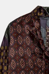 Camisa de seda con estampado tipo pañuelo en tonos marrones y ocres, cuello solapa, manga larga y detalle de pañuelo integrado en el cuello. Presenta bajo asimétrico y cierre frontal con botones.