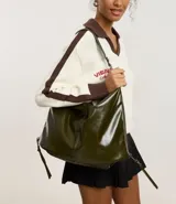 Cartera tipo hobo de gran tamaño confeccionada en poliuretano con acabado brillante. Presenta un diseño de media luna con cierre de cremallera superior, correa de hombro fija y asa larga desmontable. Incluye cierres laterales que permiten expandir su capacidad interna.