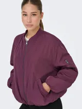 Campera bomber oversize color mauve wine, con cuello estilo baseball, cierre frontal con cremallera, bolsillo lateral y un bolsillo con cierre en la manga. Confeccionada en tejido plano con forro de poliéster.