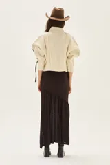 Falda larga de punto en color marrón, confeccionada en una mezcla de viscosa y lurex. Presenta un diseño de corte asimétrico con un volado en el bajo que aporta movimiento y ligereza a la prenda.