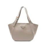 Cartera tipo tote de diseño curvo, confeccionada en cuero sintético color gris. Presenta asas regulables con hebillas metálicas y un aplique triangular metálico con el logo de la marca en el frente.