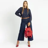 Mochila de nylon color rojo, con tapa frontal, broche metálico y cierre tipo marinero. Cuenta con bolsillo frontal con cierre metálico, bolsillos laterales, asas de mano y correas regulables para la espalda.