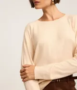 Suéter de punto color marrón chocolate, con cuello redondo y mangas largas con puños acanalados. Presenta un diseño básico y versátil de corte recto.