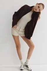 Campera oversized de sherpa suave color marrón oscuro, con cuello elevado, cierre frontal y bolsillos discretos en las costuras laterales. Presenta hombros caídos y mangas largas amplias.