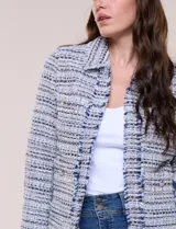 Chaqueta corta estructurada confeccionada en tejido texturado boucle estilo tweed en tonos azul, blanco y negro. Cuenta con forro interno, cuello camisero, frente abierto con bordes deshilachados, bolsillos tipo plaque al frente con botones metálicos y mangas largas.
