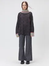 Pullover de punto jacquard con diseño de cuadros en relieve, cuello alto y mangas largas. Presenta detalles de pespuntes en color rojo en el cuello y los puños, aberturas laterales y logo bordado en el pecho.