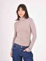 Polera de tejido de punto fino, con cuello alto doblado y mangas largas. Presenta un diseño ajustado al cuerpo con terminaciones acanaladas en puños y ruedo.