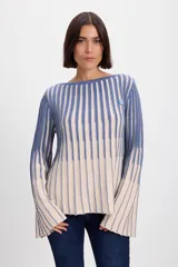 Sweater de punto con diseño de rayas verticales en dos colores, azul y crudo. Presenta cuello bote, mangas largas con terminación acampanada y un aplique decorativo en el pecho.