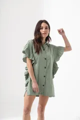 Camisa azul de corte holgado, con cuello clásico, cierre frontal con botones, mangas cortas con volados y largo hasta la mitad del muslo.