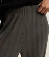 Pantalón de corte recto con cintura alta elástica, confeccionado en tejido acanalado con textura rayada en relieve. Presenta un diseño cómodo y versátil, ideal para uso diario.