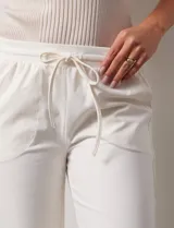 Pantalón jogger color crema, de corte ancho, con pretina elastizada y lazo de ajuste.