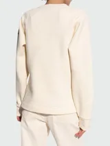 Buzo de algodón color crema, de cuello redondo y manga larga, con logo bordado en el frente.