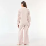 Pijama de dos piezas confeccionado en popelina con estampado de cuadros vichy en color rosa. La parte superior es una camisa de manga larga con puños con volados y cierre frontal de botones. El pantalón es de corte recto y holgado, con detalle de volados en el ruedo.