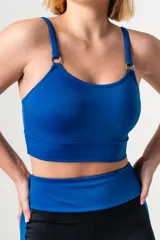 Top deportivo de color azul francia, con escote redondo, breteles finos ajustables y detalle de aros metálicos en la unión de los breteles con el frente. Presenta una faja ancha de doble tela en la base para mayor soporte.