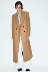 Abrigo largo negro ZARA Woman Collection de corte recto, confeccionado con hilatura de lana. Presenta cuello con solapa de muesca, cierre cruzado de doble botonadura frontal y bolsillos ribeteados en los laterales.