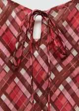 Vestido largo de tirantes finos con estampado de cuadros en tonos rojizos y marrones. Presenta un diseño recto, tejido fluido y un lazo decorativo en el escote.
