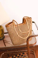 Bolso tipo tote bag de cuero trenzado a mano, en tonos beige y marrón claro, con asas trenzadas.