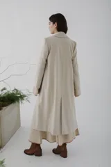 Tapado largo de paño en color beige, con solapas clásicas, cierre frontal de dos botones y corte recto estructurado.