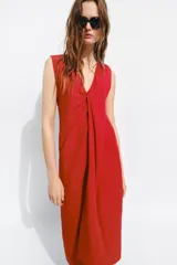 Vestido midi de Zara Woman Collection color rojo, confeccionado con mezcla de lino. Presenta escote en V pronunciado, mangas sisa y un diseño con frunce delantero y detalle drapeado. Cuenta con bajo recto y cierre lateral con cremallera oculta.