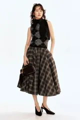 Top sin mangas de punto suave con mezcla de mohair y lana, con estampado de rombos en tonos negro y gris. Presenta un cuello tipo bufanda integrado con abertura para cruzar y remate acanalado en el bajo.