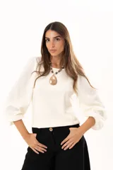 Blusa de cuello redondo con mangas largas tipo globo y puños elásticos. Presenta un diseño de textura combinada en el frente y las mangas.