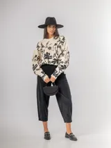 Sweater de punto con calce oversized, fondo color crudo y diseño estampado de flores en color negro. Presenta cuello redondo y mangas largas.
