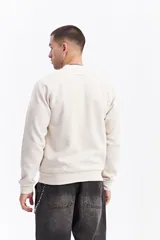 Campera tipo bomber color beige, con cierre frontal completo, cuello redondo y puños elásticos. Presenta una textura sutil en la tela y un calce cómodo.