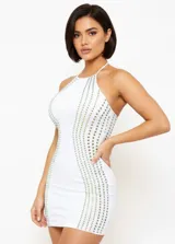 Vestido corto ajustado de color blanco con cuello halter. Presenta paneles laterales decorados con pedrería brillante dispuesta en líneas verticales.