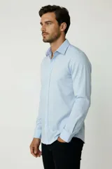 Camisa blanca de algodón, de diseño holgado y manga larga, con cuello camisero y cierre frontal de botones.