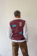 Chaleco tejido a mano en lana merino, con escote en V, cierre frontal de botones de madera y diseño con detalles geométricos de colores.