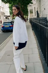 Camisa blanca de algodón con cuello solapa, manga larga y cierre frontal de botones.