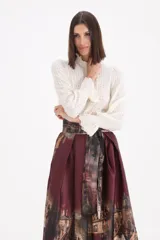 Sweater de punto calado en color crudo, con cuello alto tipo polera y mangas largas con puños con volados.