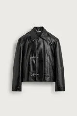 Cazadora regular fit negra de efecto piel, con cuello solapa, manga larga y bolsillos en la cadera. Cuenta con cierre frontal de cremallera oculta por solapa con alamares metálicos.