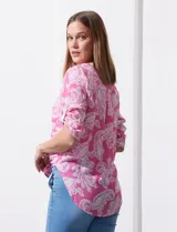 Blusa celeste con estampado blanco, de gasa, con cuello a la base y escote en V. Tiene abertura con botones, bolsillos delanteros y mangas 3/4 regulables con presilla y botón. El ruedo termina con un nudo.