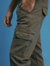 Pantalon cargo de corte recto en color verde militar, confeccionado en sarga de algodón con elastano. Presenta bolsillos laterales con fuelle y tapa, además de bolsillos traseros con cierre de botón.