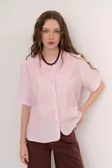 Camisa de manga corta color blanco con cuello mao y cierre frontal de botones. Presenta detalles bordados tono sobre tono en el canesú y diseño de corte recto.