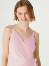 Vestido corto color rosa, con escote cruzado, sin mangas y lazo en la cintura.