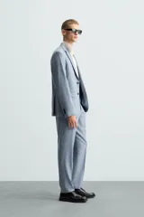 Pantalón de vestir corte slim fit, confeccionado en tejido con lana, con bolsillos frontales y traseros de doble vivo con botón.