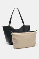 Bolso tipo shopper de hombro en color beige, con diseño estructurado, doble asa y detalle de pespuntes verticales en el cuerpo. Incluye un colgante decorativo tipo etiqueta y cierre imantado.