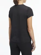 Blusa negra de satén con mangas cortas, cuello redondo con abertura en forma de V y cierre metálico.