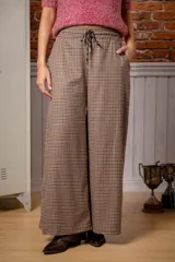 Pantalón de corte ancho y tiro alto, con estampado de cuadros pequeños en tonos marrones y negros. Cuenta con cintura elástica y cordón ajustable.