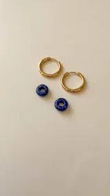 Aros de acero quirúrgico dorados en forma de argolla con dijes de piedra natural negra en forma de dona, desmontables.