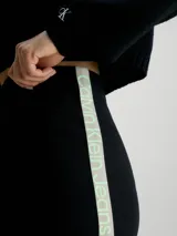 Falda corta negra de tejido acanalado, corte slim y cintura elástica. Presenta una cinta con logo en el lateral izquierdo en tonos verde y negro.